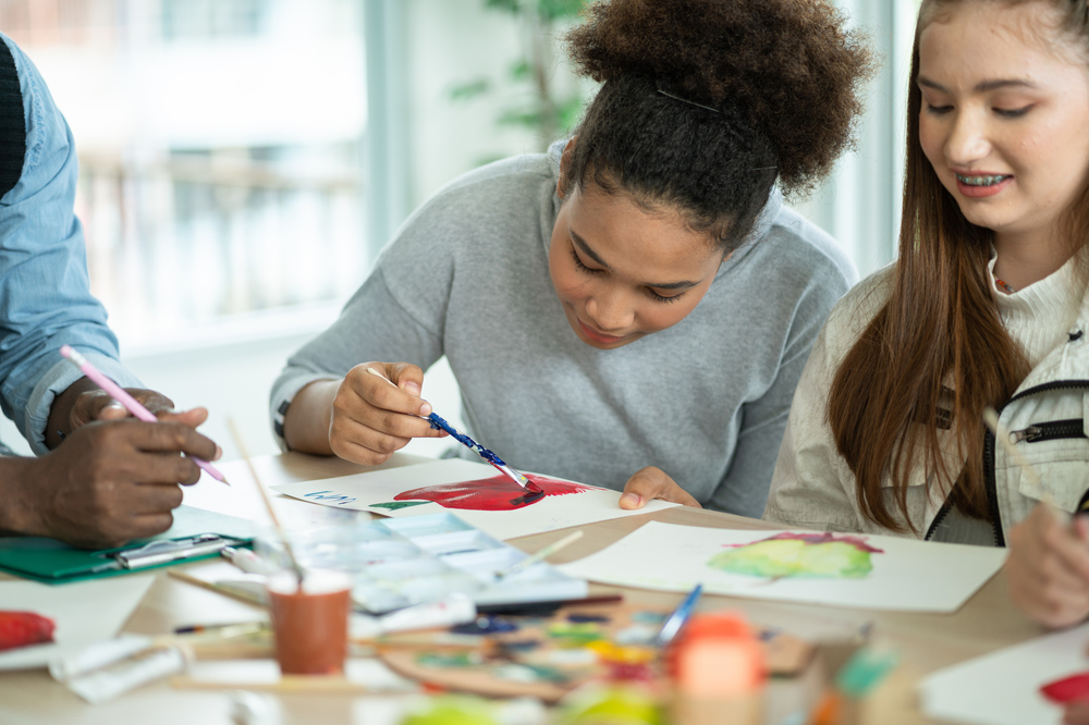 Group Of Diversity Students Enjoy Drawing And Painting In Arts Class With Friends. Happy Smiling Kids Using Paintbrush Sketching On Paper. Support Creative Skill In A Classroom At School.