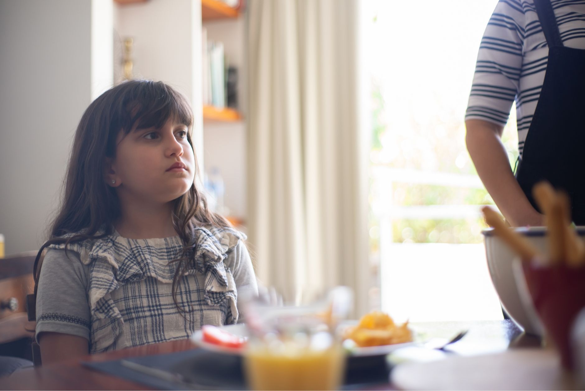 Young girl looking away during family conversation at breakfast table